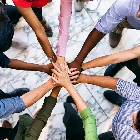 Diverse team joining hands together representing equality, diversity and inclusion at work